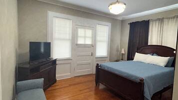A bedroom with a bed, a TV, a bench, and a ceiling light.