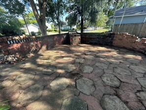 Un patio pavimentado con baldosas de piedra hexagonales, un muro de ladrillo y una valla de madera.