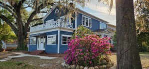 A two-story house with a porch, surrounded by trees and a flowering bush. - Historic Fleming House, 4BR 3BA, Sleeps 8-10, 3-5 Min Walk to Square (Bainbridge)