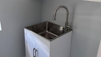 A compact kitchen with white cabinets, a stainless steel sink, and a marble-tiled floor.