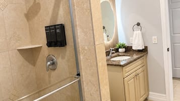 A bathroom with a shower, vanity, and toilet.