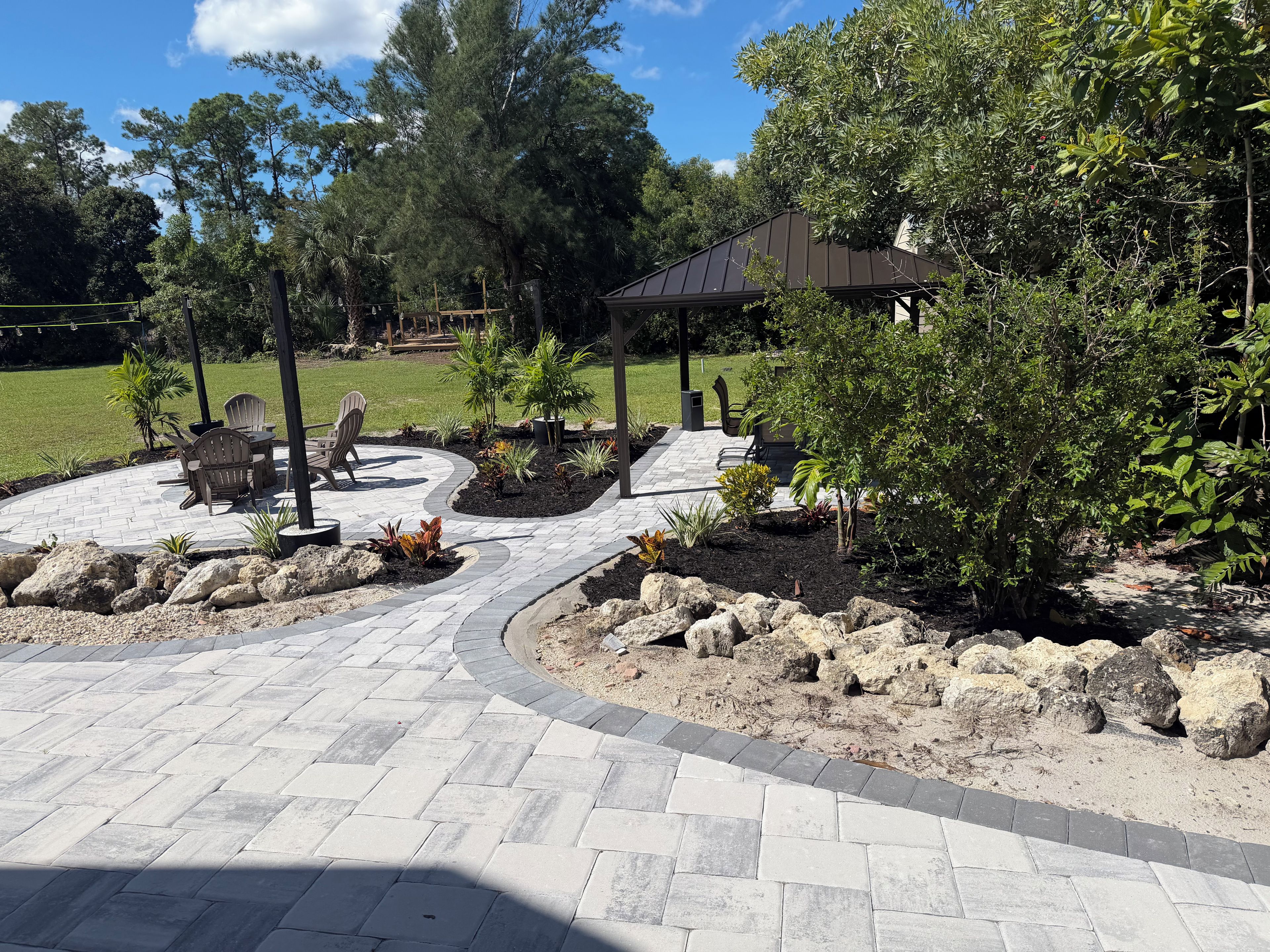 A patio area with a curved stone pathway, outdoor furniture, and a gazebo.