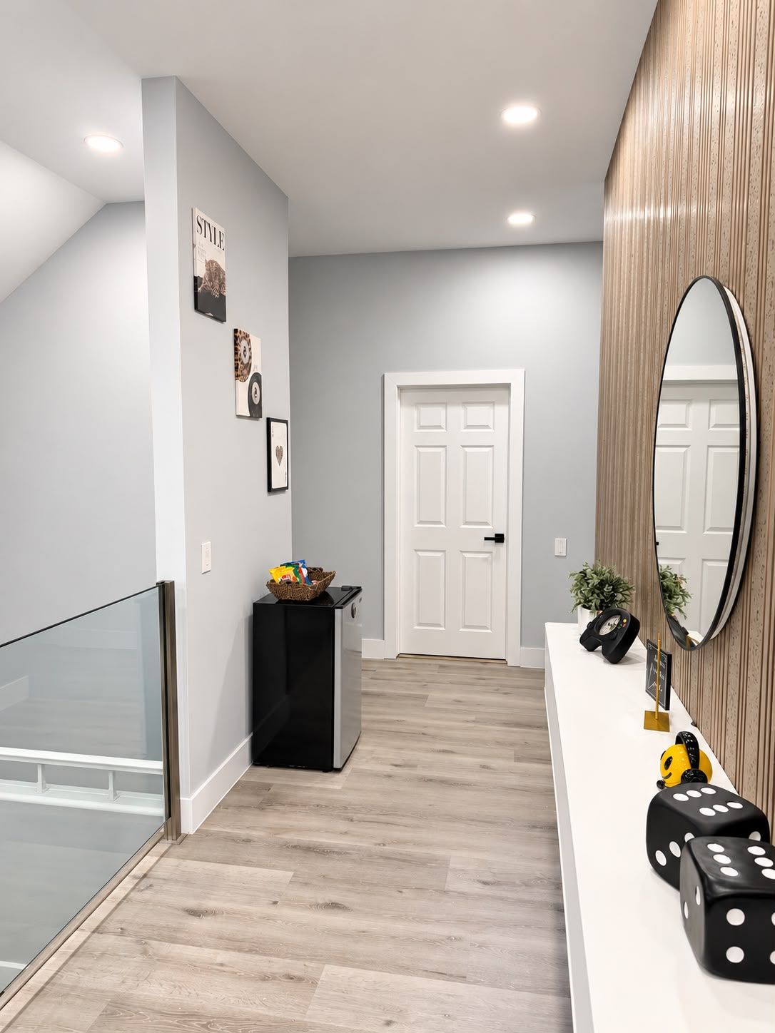 A modern hallway with a white door, a black trash bin, and a white console with a mirror and dice.