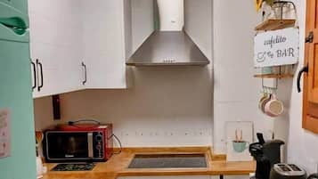 A compact kitchen with white cabinets, a microwave, a stove, and a sink.
