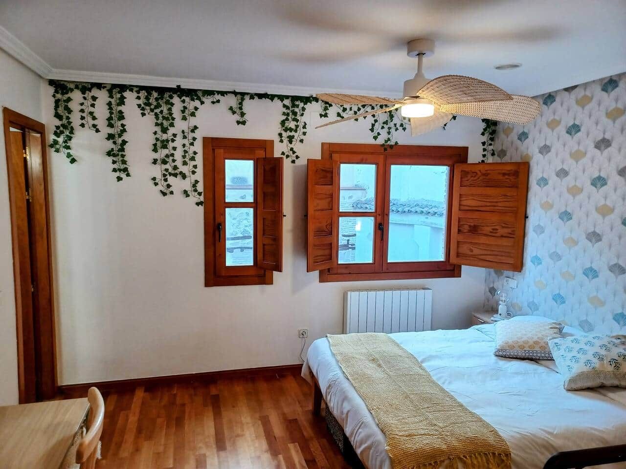 Una camera da letto con un letto, persiane in legno, un termosifone e una finestra con vista.