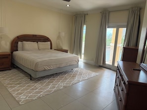 A bedroom with a large bed, a nightstand, a dresser, and a balcony view. - Spacious Island Oasis. Beautiful waterfront condo with naturally light and charm (Freeport)