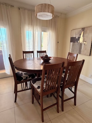 Un comedor con una mesa redonda de madera, seis sillas y un cuenco de aperitivos.