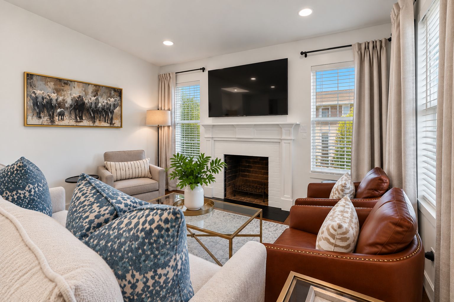 A living room with a fireplace, sofa, armchair, and a flat-screen TV mounted above it.