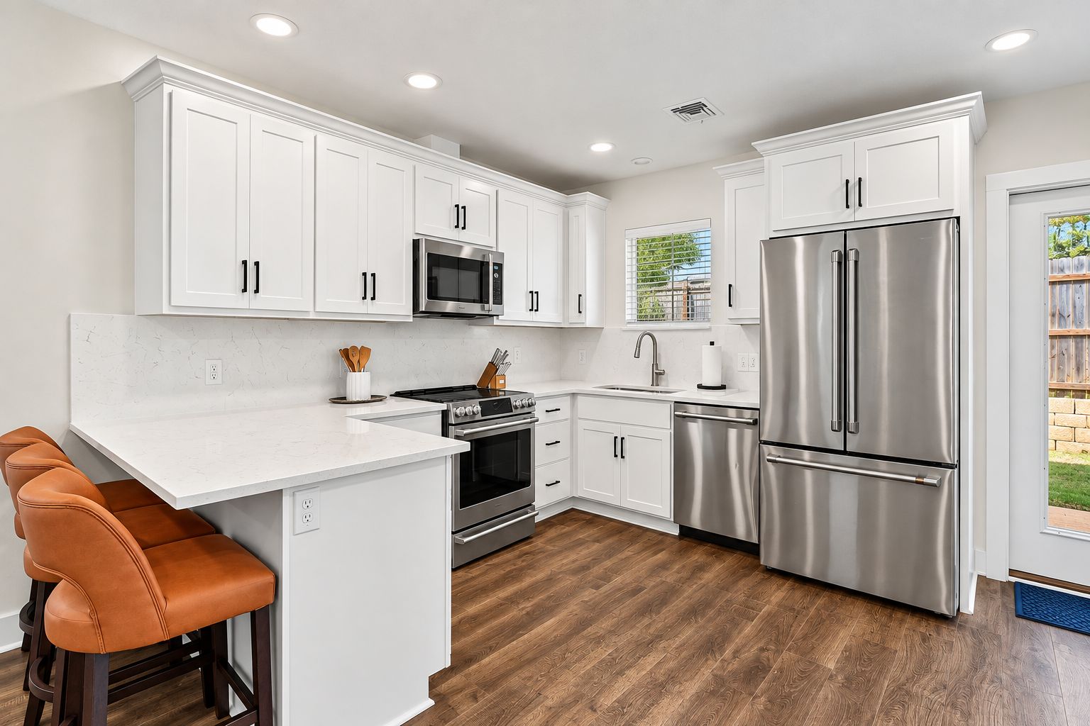 A modern kitchen with white cabinetry, stainless steel appliances, and a wooden floor.