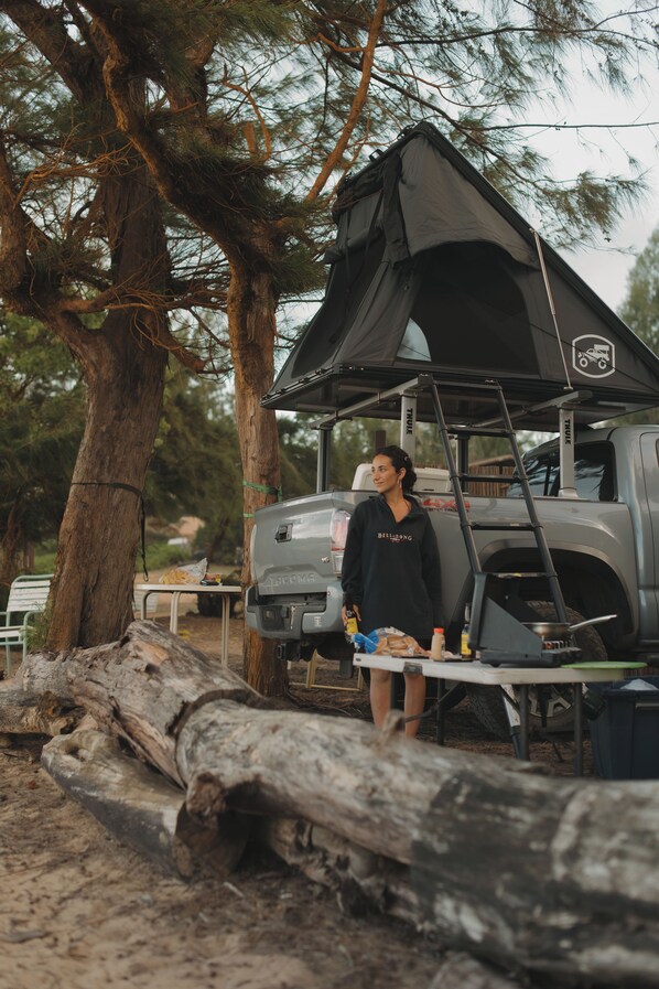 Un campamento con una tienda de campaña, una camioneta y una mesa con equipo de acampada.