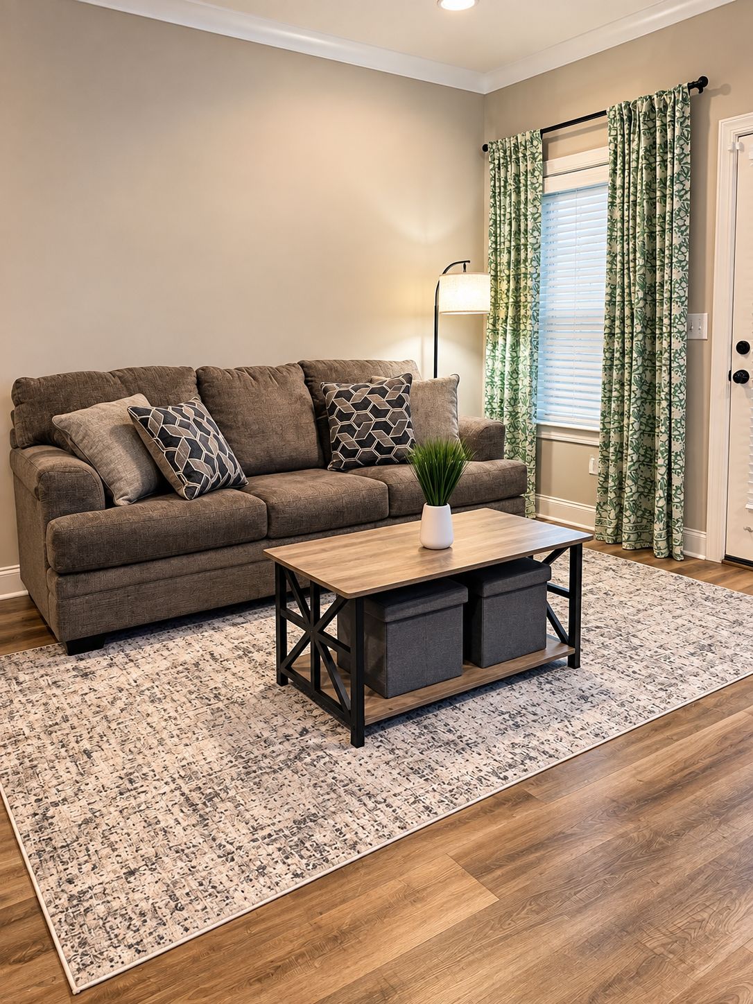 A living room with a sofa, a coffee table, a lamp, and a window with curtains.