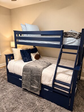 Una cama litera con un cajón para guardar objetos, una lámpara y una alfombra mullida.