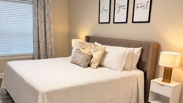A bedroom with a bed, a nightstand, a ceiling fan, and three framed quotes on the wall.