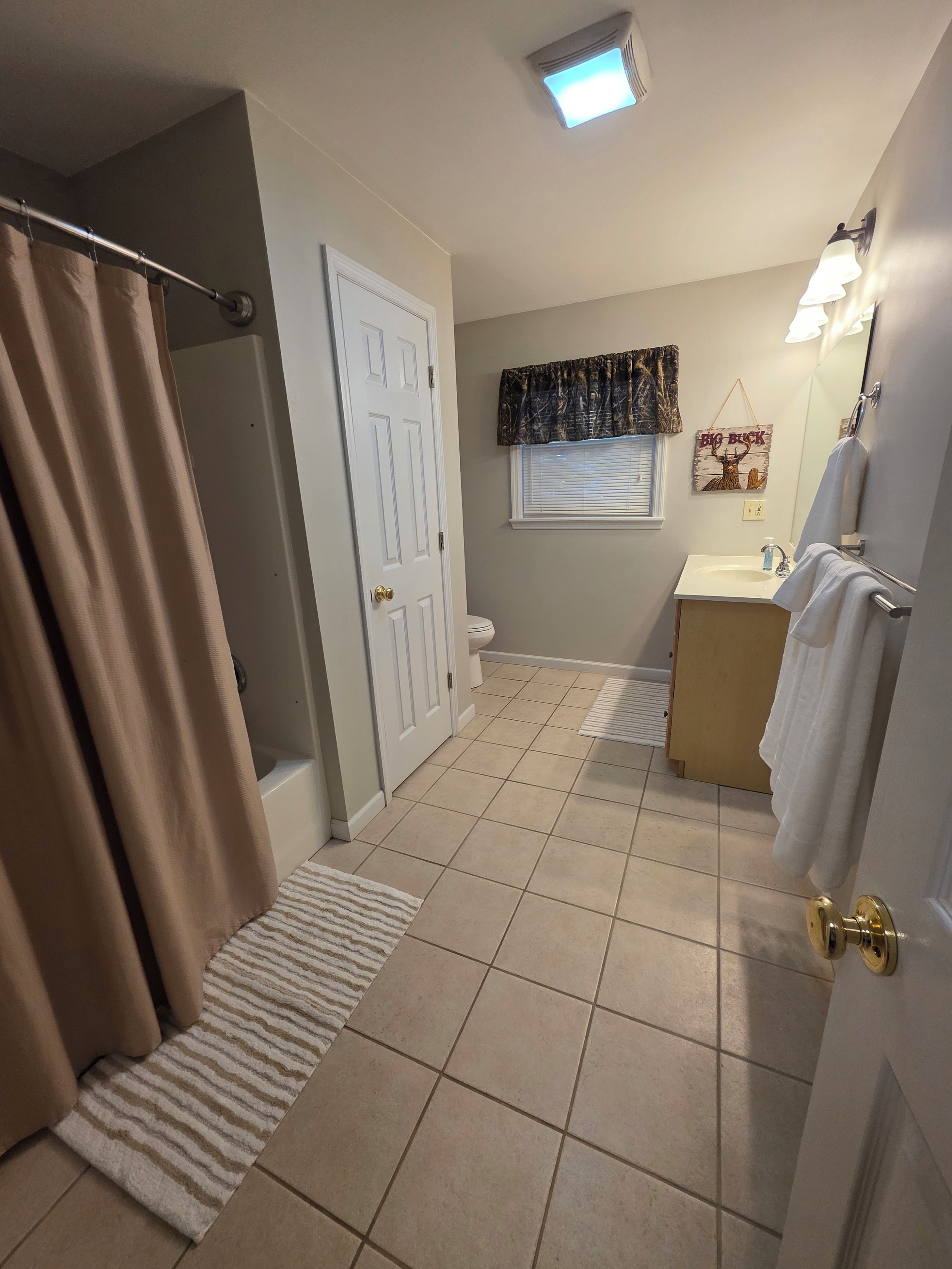 Een badkamer met een douche, toilet, wastafel en een handdoekhouder.