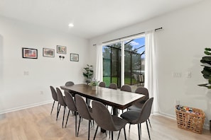 A dining area with a wooden table and chairs, a potted plant, and a view through a glass door to an outdoor space. - Best location near Orlando’s world famous attractions (Kissimmee)