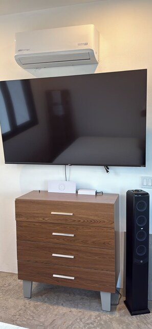 Un téléviseur à écran plat fixé au mur, au-dessus d’un meuble en bois doté de tiroirs.