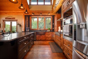 A kitchen with wooden cabinets, a stainless steel refrigerator, and a large window.