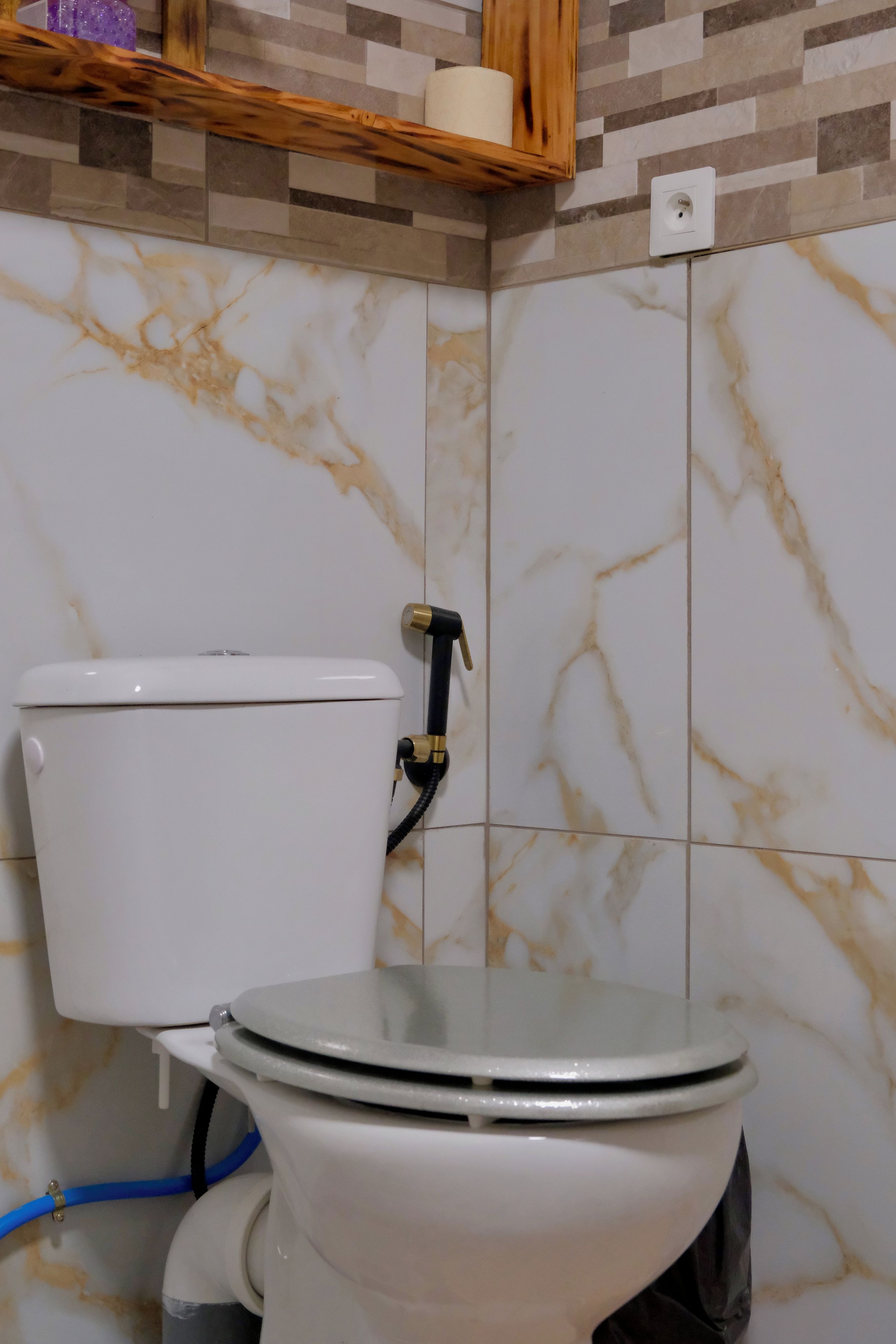 A toilet with a marble-patterned wall behind it.