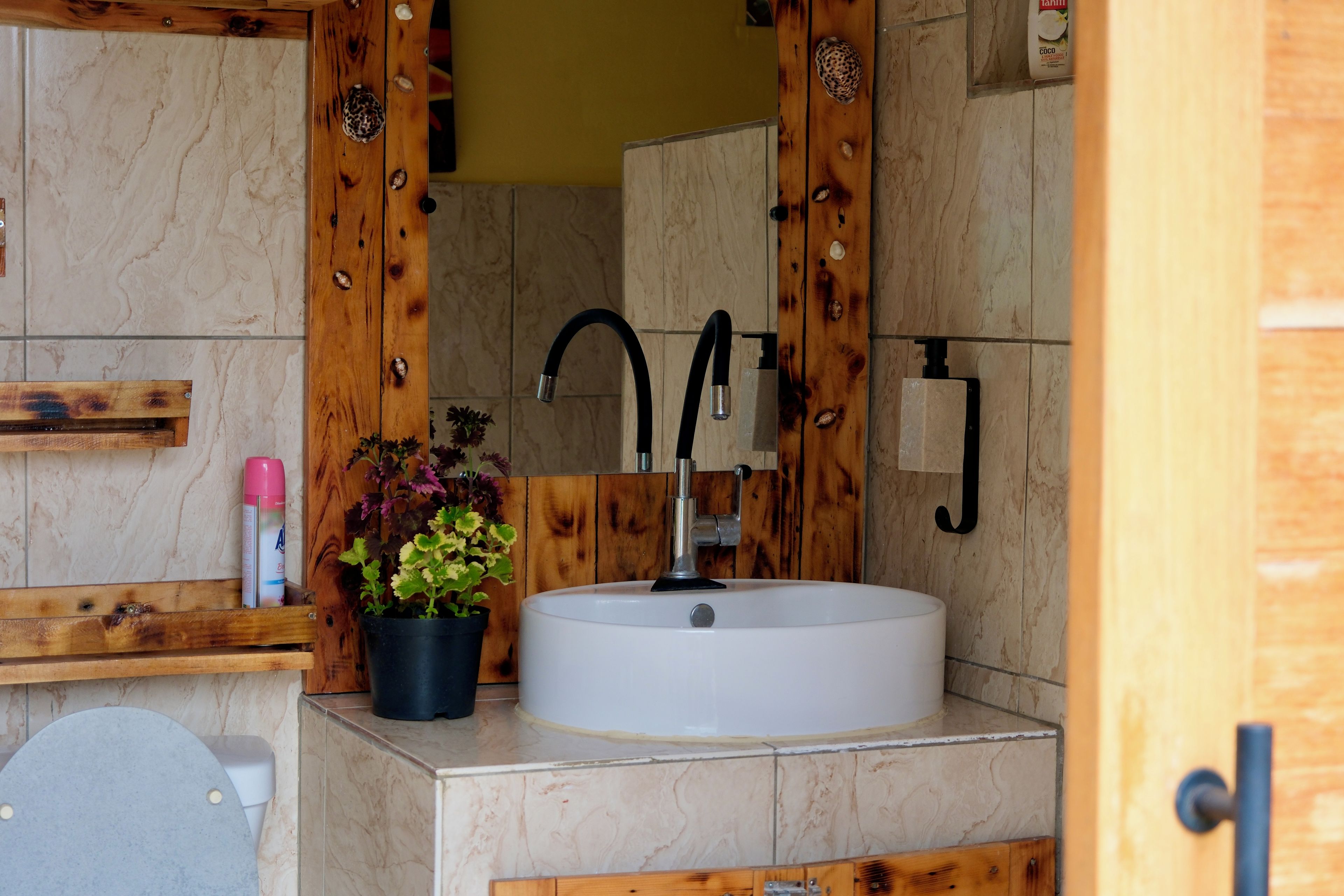 Une salle de bain avec un meuble-lavabo en bois, un lavabo blanc, un miroir et un espace douche.