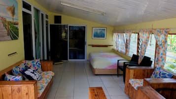 A room with a bed, wooden furniture, a window with curtains, and a door leading outside.
