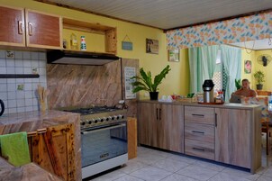 Una cocina con estufa, horno y armarios de madera. Hay una planta en la encimera y un cartel en la pared.