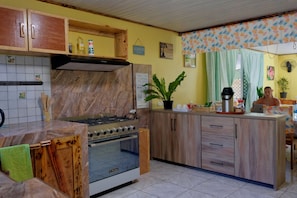 A kitchen with a stove, oven, and wooden cabinets. There is a plant on the counter and a sign on the wall. - Povai lodge (Bora-Bora)
