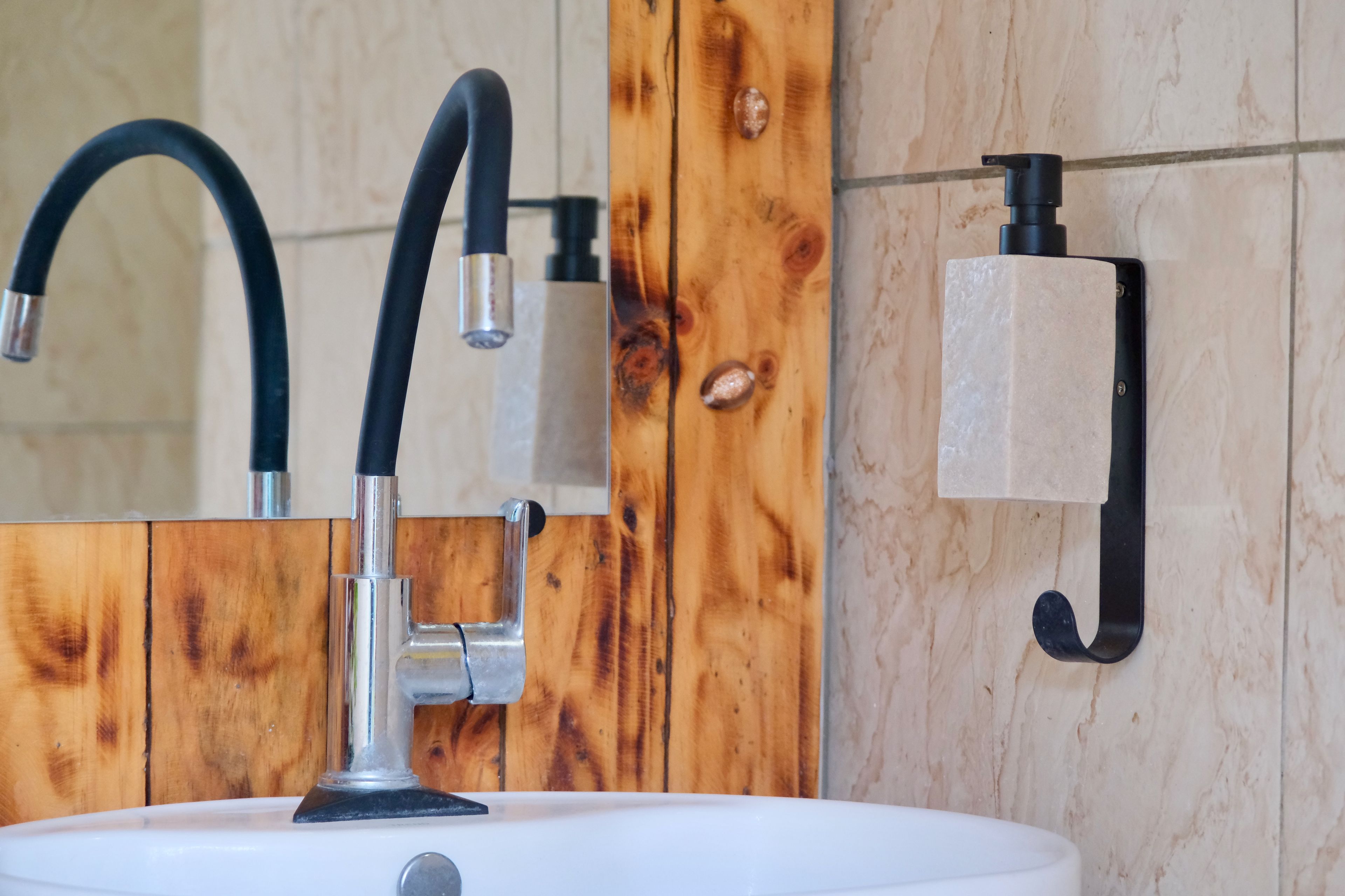 A bathroom with a white sink, a black faucet, and a wooden wall panel.