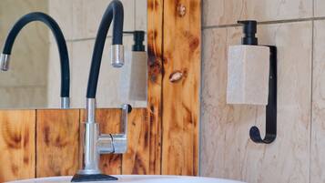 A bathroom with a white sink, a black faucet, and a wooden wall panel.