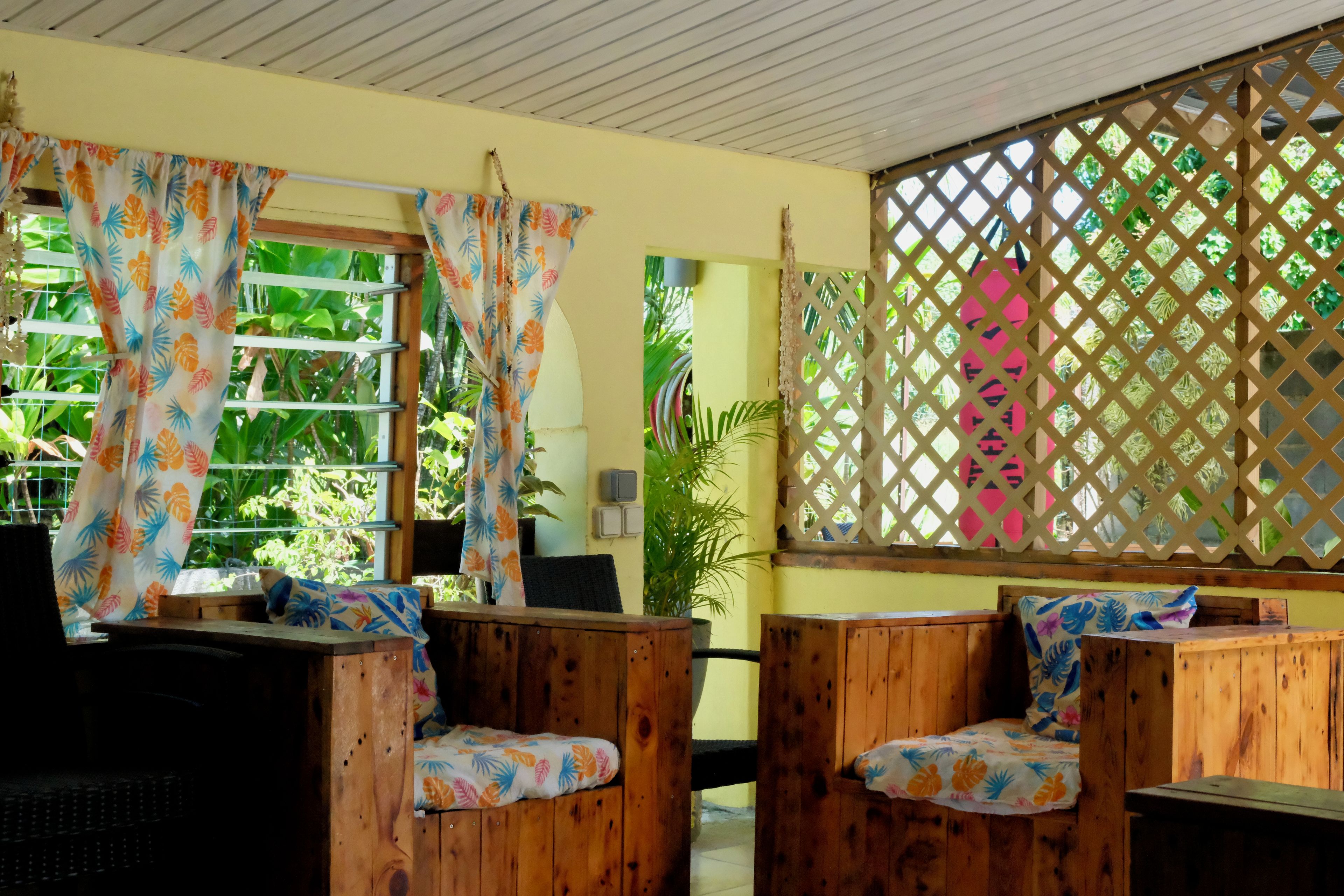 A room with wooden furniture, a window with curtains, and a lattice screen.