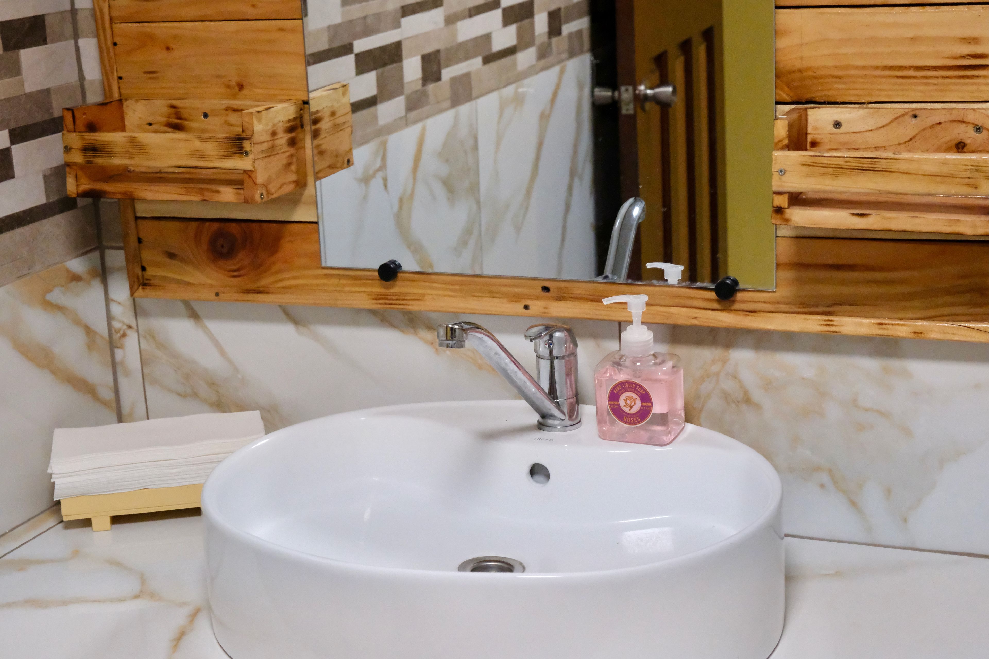 Un baño con un lavamanos blanco, un espejo y muebles de madera.
