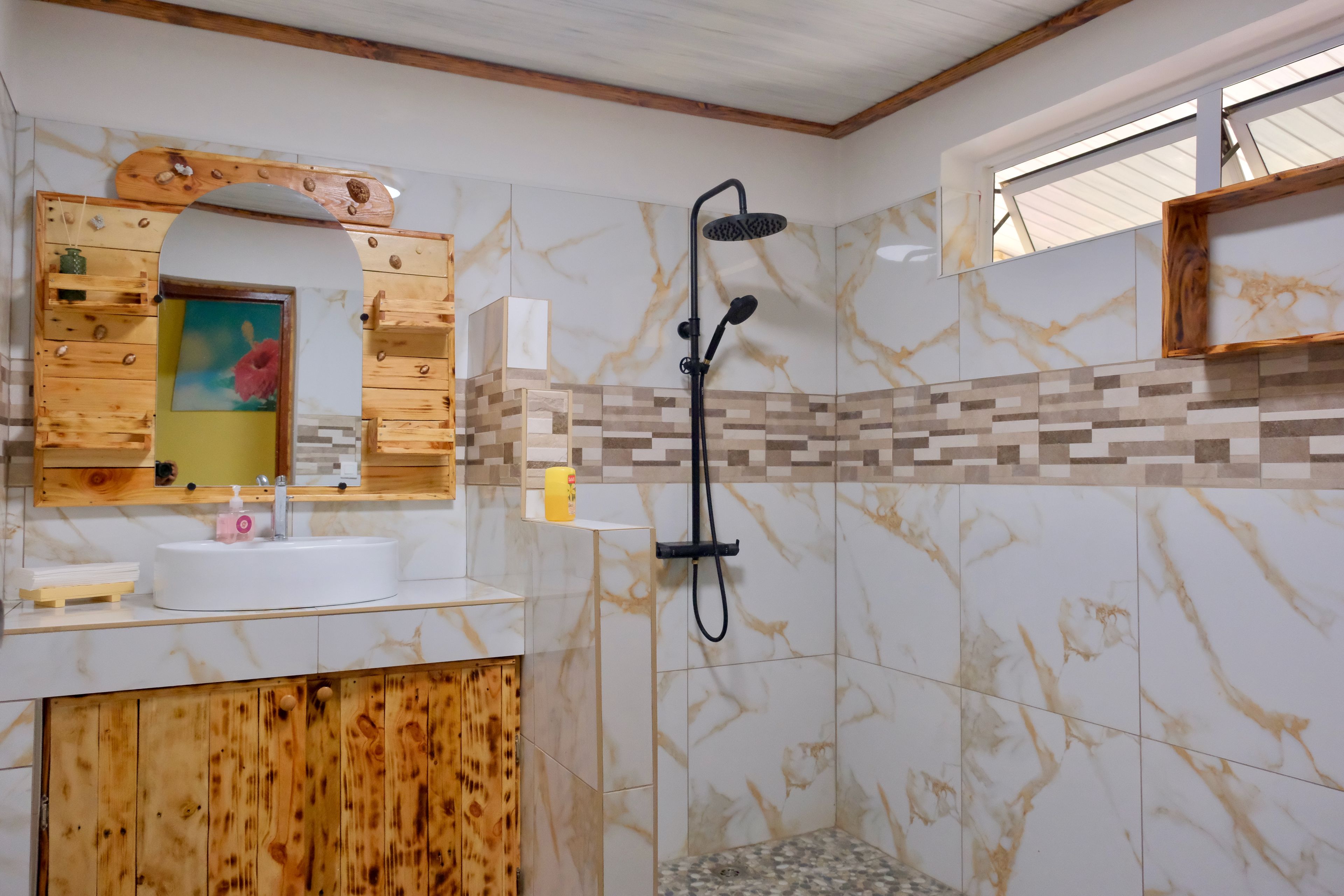 A bathroom with a wooden vanity, a sink, a mirror, and a shower with a handheld showerhead.