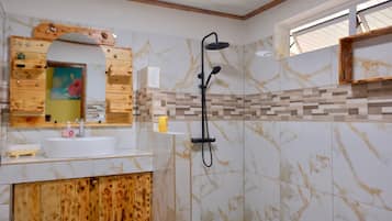 A bathroom with a wooden vanity, a sink, a mirror, and a shower with a handheld showerhead.