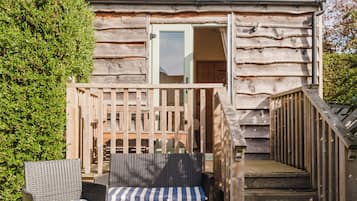 A wooden cabin with a balcony, outdoor seating, and a staircase leading to the entrance.