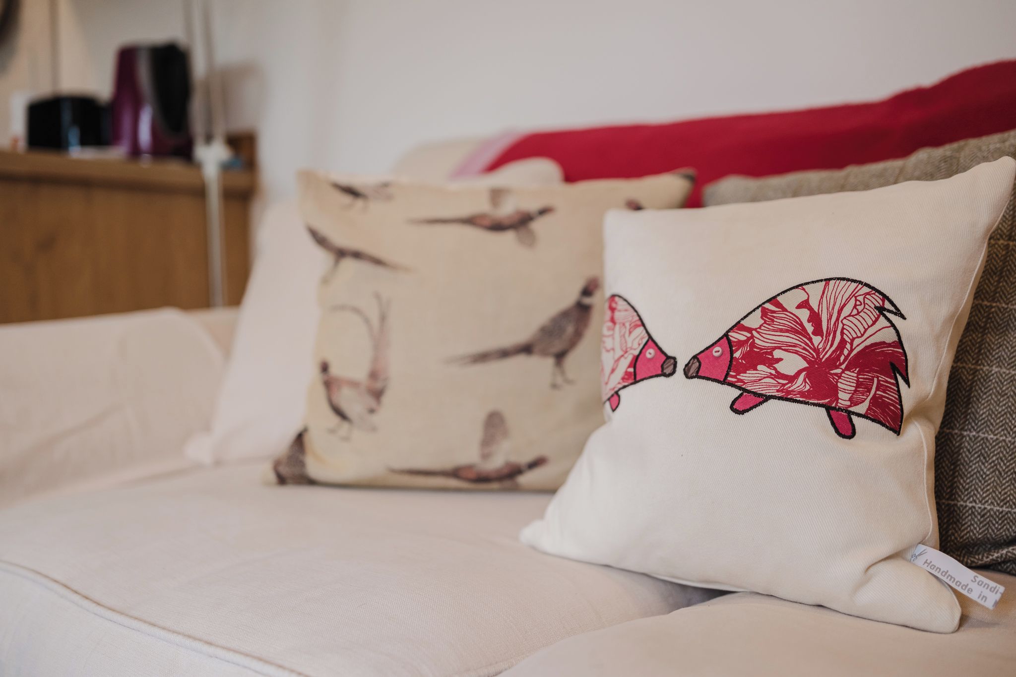 A bed with two pillows, one with a bird pattern and another with a red design.