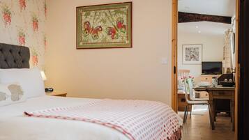 A bedroom with a bed, a desk, and a chair. There is a painting on the wall and a window.