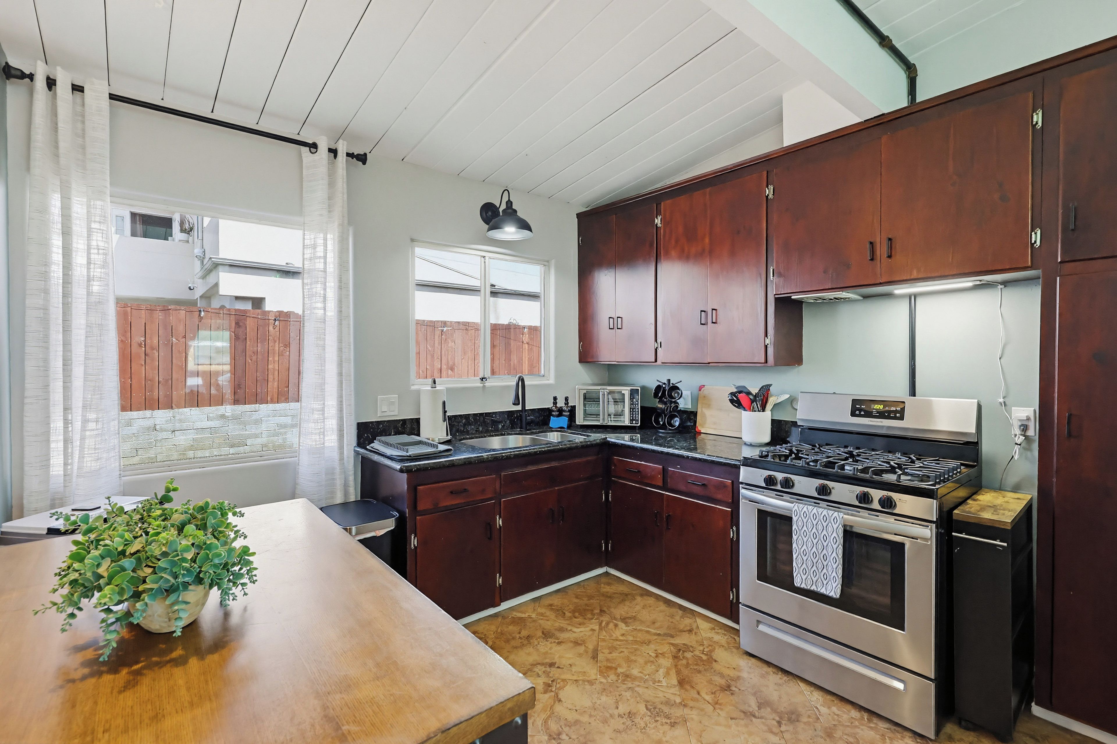 A kitchen with wooden cabinets, a stove, a microwave, and a sink.