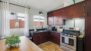 A kitchen with wooden cabinets, a stove, a microwave, and a sink.