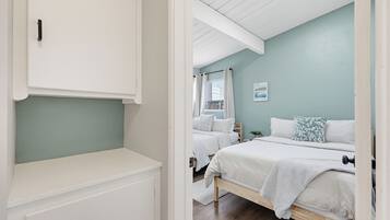 A bedroom with a bed, a nightstand, a window with curtains, and a wall-mounted shelf.