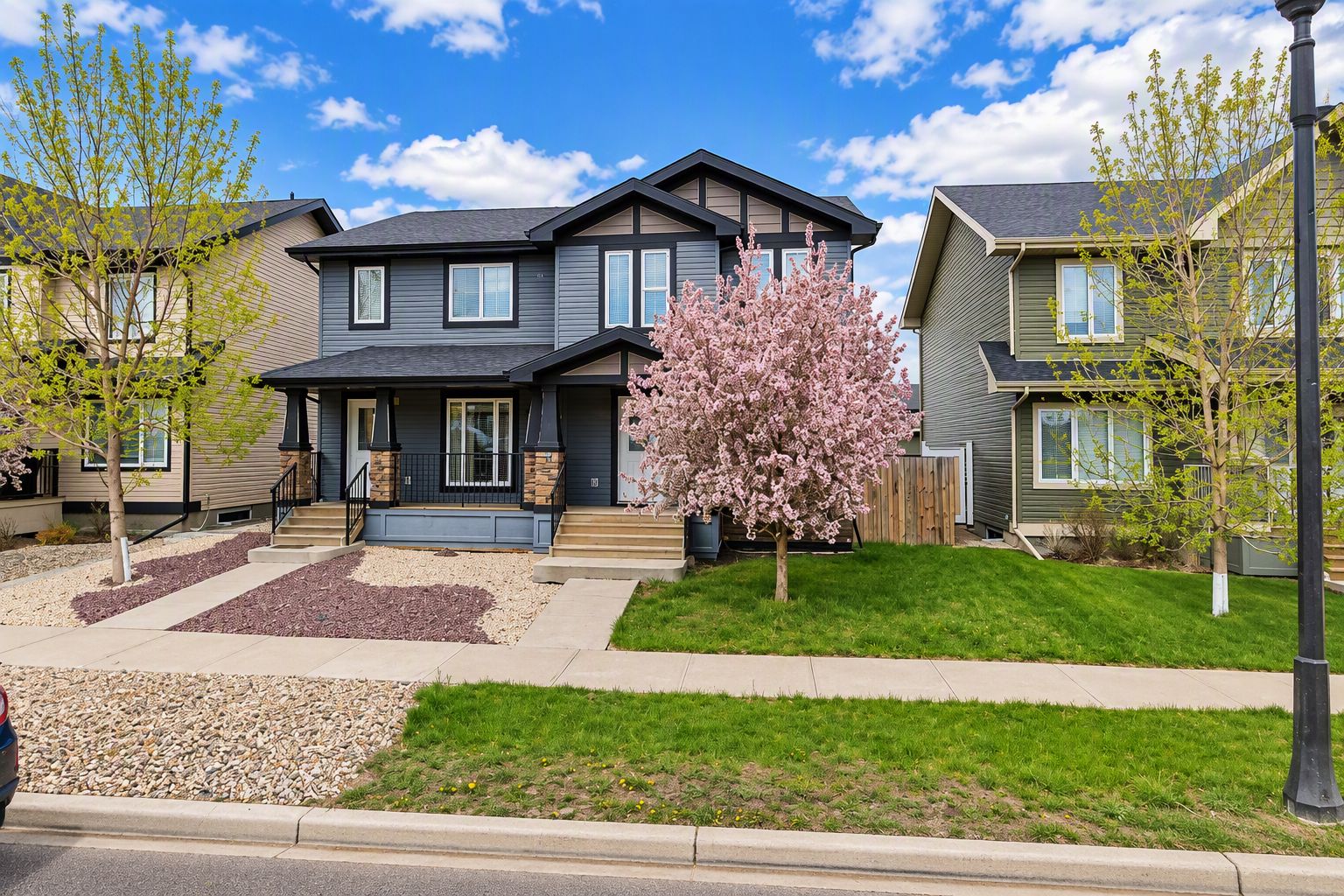 A residential area with houses featuring front porches, a well-maintained lawn, and a clear sky.