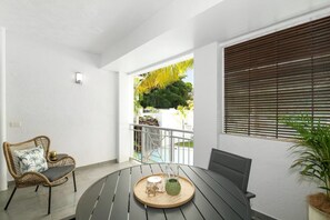 A balcony with a round table, a wicker chair, and a potted plant.
