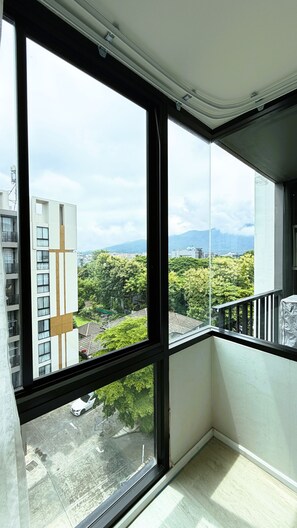 A room with large windows offering a view of a building and greenery. - 707 Cozy 1-bedroom Condo in Nimman - 4 mins walk to Maya Mall and One Nimman (Chiang Mai)