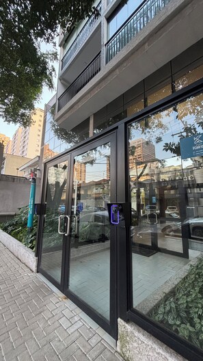 A modern building with large glass windows, a metal gate, and a balcony. - Modern studio/apartment in Tatuapé - excellent location! (São Paulo)
