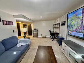 A living room with a sofa, a coffee table, a TV, and a dining area with a table and chairs. - Rose Park Cottage | Near Downtown | Mid-Term (Salt Lake City)