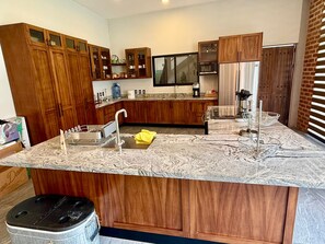 A modern kitchen with wooden cabinets, a granite countertop, and a built-in oven. - 5-SUITE VACATION HOME WITH A LARGE PRIVATE POOL (Cruz de Huanacaxtle)