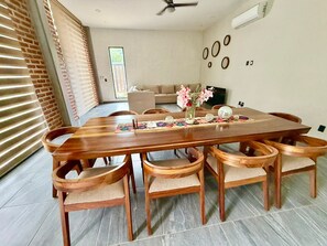A dining area with a wooden table and chairs, a vase with flowers, and a wall with circular decorations. - 5-SUITE VACATION HOME WITH A LARGE PRIVATE POOL (Cruz de Huanacaxtle)