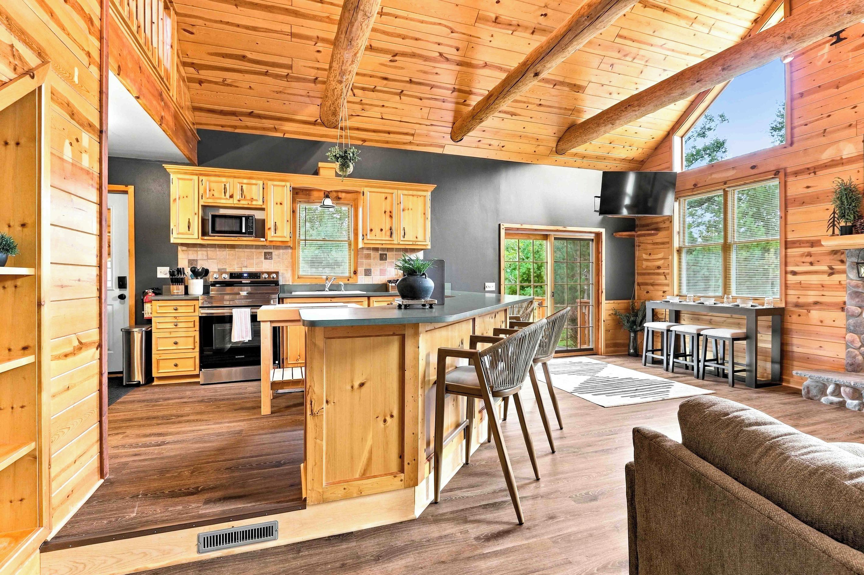 A spacious kitchen with wooden cabinets, a central island, and a dining area with a stone fireplace.