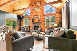 A cozy cabin interior with a fireplace, wooden walls, and a dining area. - Timber Nook -2BR Near Sand Valley & Lake Arrowhead (Nekoosa)