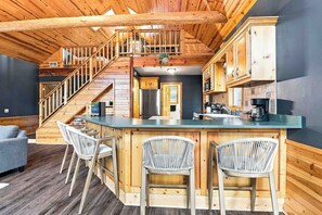 Een houten interieur met een keuken, een bar en een trap.