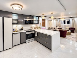 A modern kitchen with a central island, built-in appliances, and a dining area with a red sofa and a round coffee table. - Gold Luxury 3BR-Art District-City and Ocean Views (San Juan)