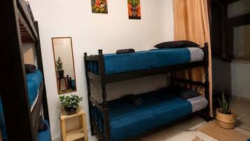 A compact room with bunk beds, a small table with a plant, and two wall-mounted paintings.